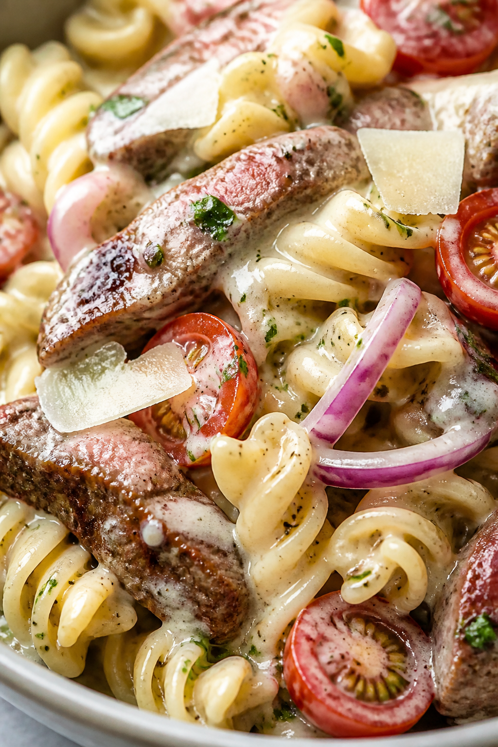 Close-up detail – Creamy garlic-Parmesan dressing coating pasta and beef: Macro shot of rotini pas
