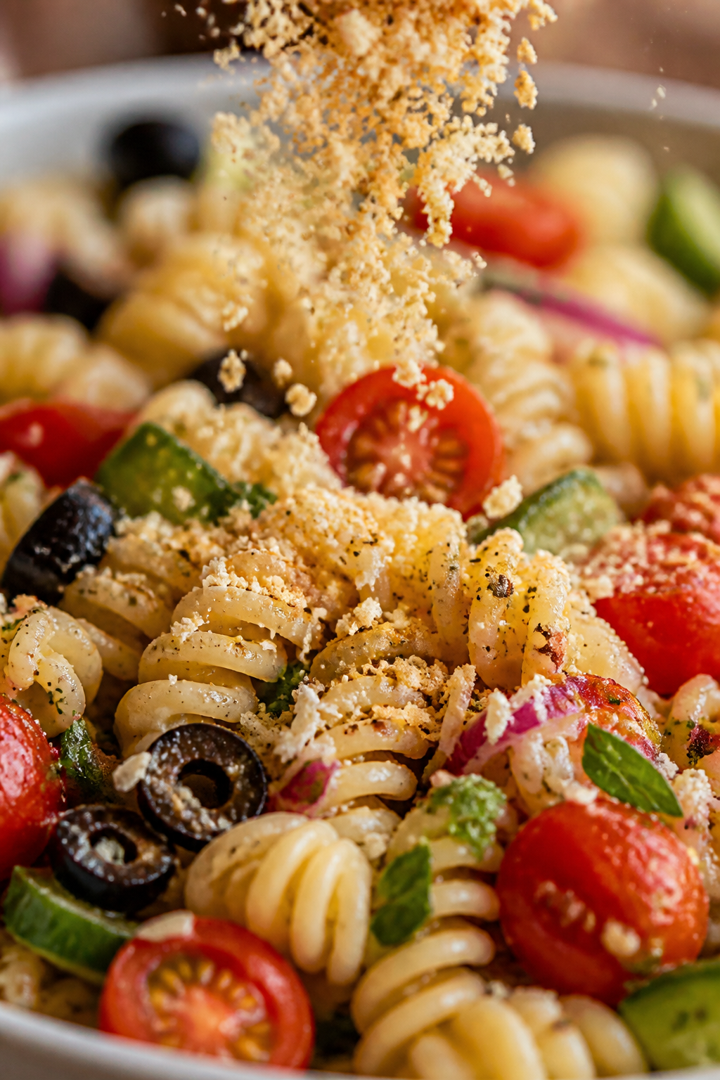 Close-up detail of finishing touch: Parm-crumbs being sprinkled over the assembled salad right befor