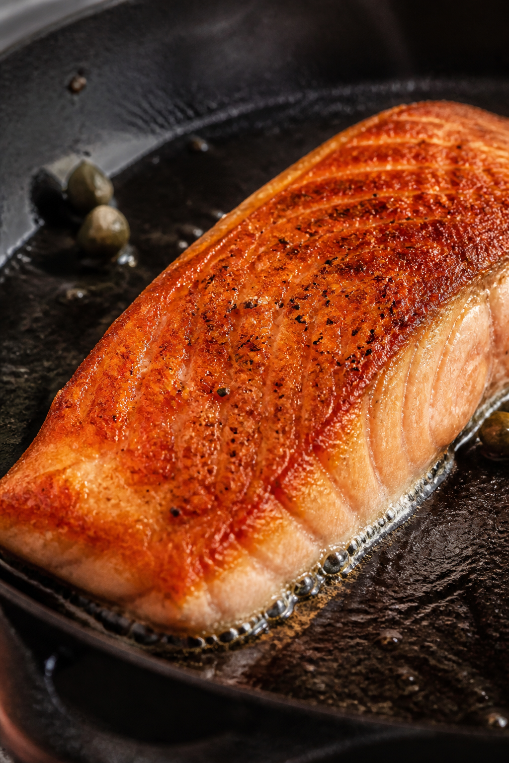 Close-up detail: Searing salmon fillet, skin side down in a cast-iron skillet, golden crispy skin wi