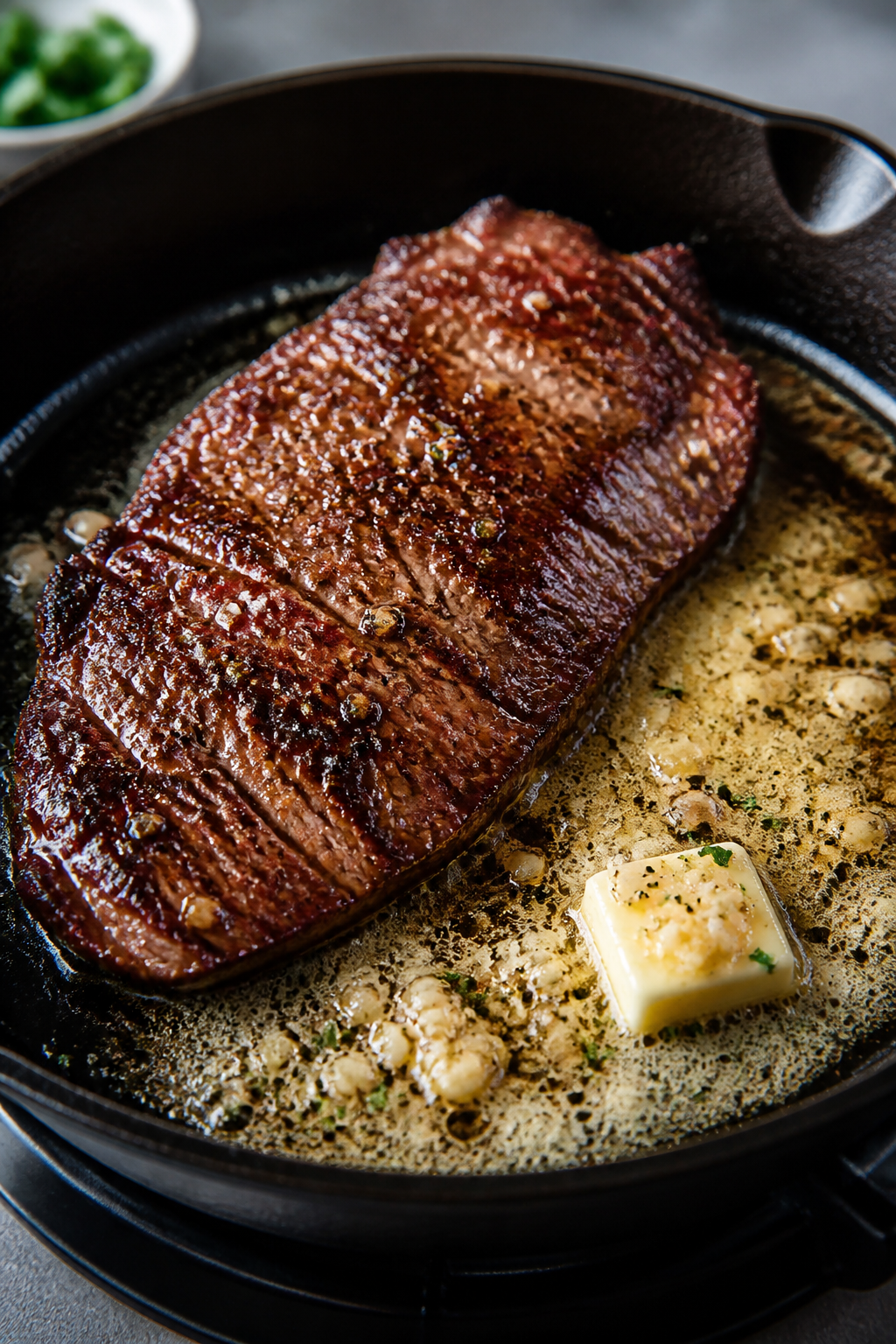 Cooking process close-up: Searing a seasoned flank steak in a hot cast-iron skillet, deep brown crus