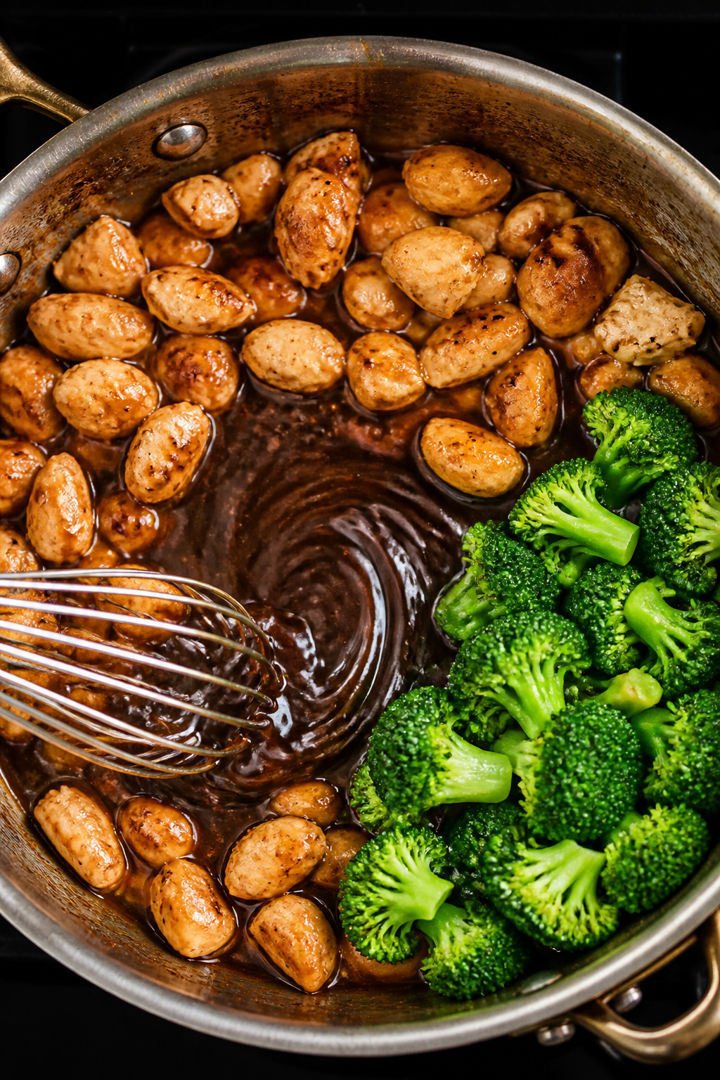 Cooking process: Overhead shot of the sauce thickening stage in a wide sauté pan—chicken pushed t