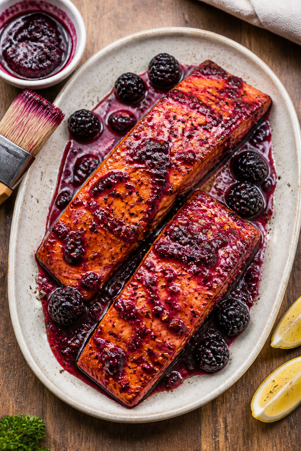 Tasty top view: Overhead shot of two glazed salmon fillets on a shallow ceramic platter, extra sauce