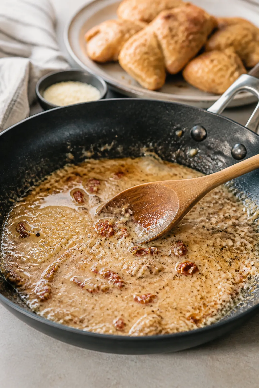 Cooking process: Skillet scene mid-deglaze—sauce base reducing after scraping browned fond; visibl