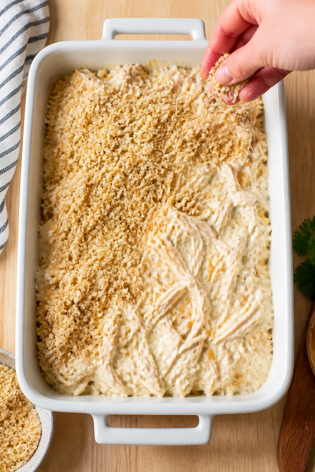 Cooking process: The casserole mixture being smoothed into a 9x13 baking dish with a spatula—visib