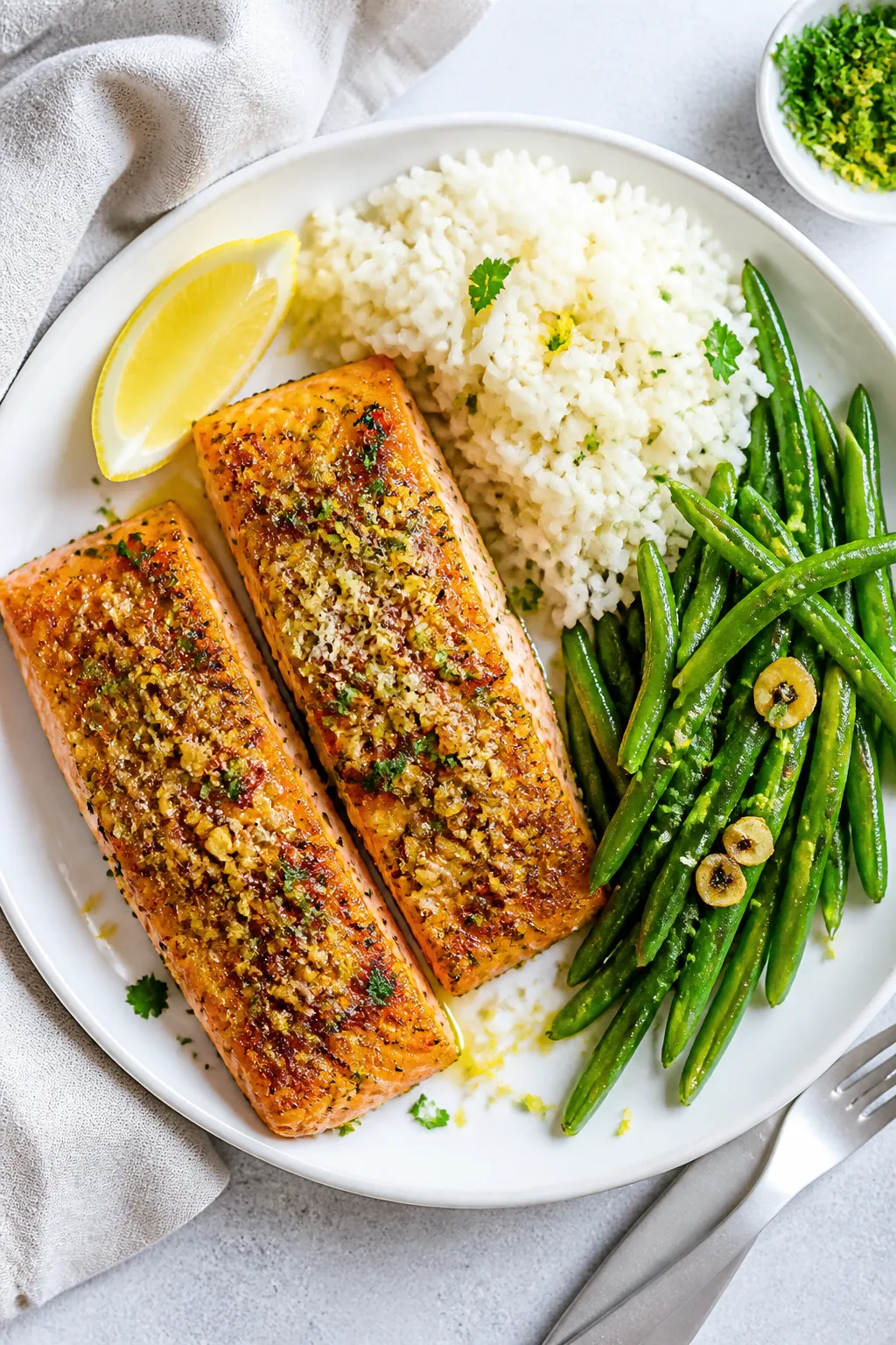 Overhead “tasty top view”: Two cooked salmon fillets with a deeply browned garlic-parmesan toppi