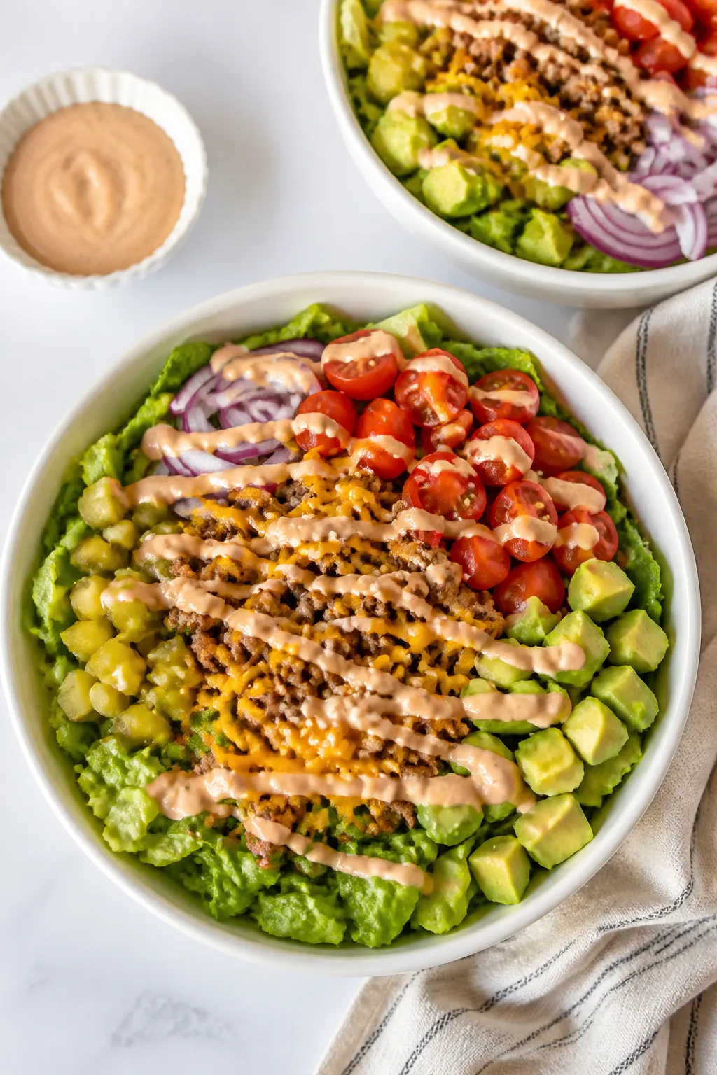 Tasty top view: Overhead shot of assembled Low Carb Cheeseburger Bowls in matte white bowls—bed of
